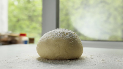 Homemade pizza dough on a light table against the window