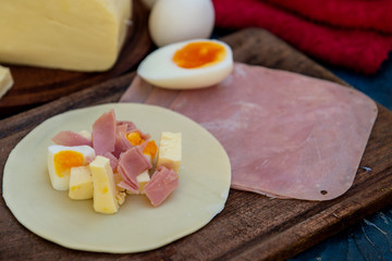 Empanada de jamón y quesos, sus ingredientes,   primer plano sobre una tabla de madera rústica