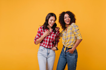 Perky girls in stylish street costumes are having fun. Brunette with bright smiles posing on isolated background