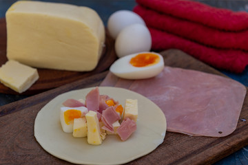Empanada de jamón y quesos, sus ingredientes,   primer plano sobre una tabla de madera rústica