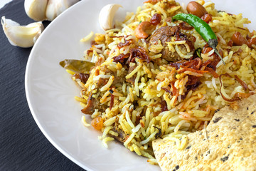 Halal Indian chicken Biryani served with yogurt tomato raita over white background. Selective focus.