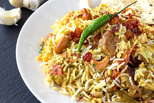 Halal Indian chicken or mutton Biryani served with yogurt tomato raita over white background. Selective focus.