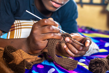 skilled young black boy knitting at home