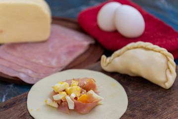 Empanada de jamón y quesos, sus ingredientes,   primer plano sobre una tabla de madera rústica