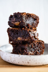 Chocolate brownie on a white plate and wood surface