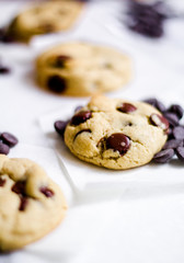 Chocolate chip cookie with vanilla dough on an white surface with glass of milk