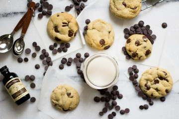 Chocolate chip cookie with vanilla dough on an white surface with glass of milk