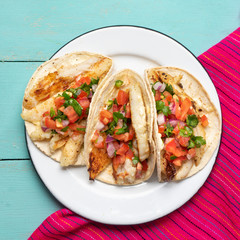 Mexican fish tacos also called Baja with fresh sauce on turquoise background