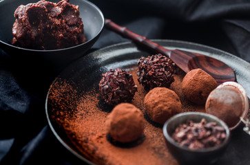 Date energy ball with cocoa on a black dish and cocoa nibs