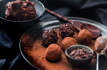 Date energy ball with cocoa on a black dish and cocoa nibs