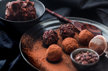 Date energy ball with cocoa on a black dish and cocoa nibs