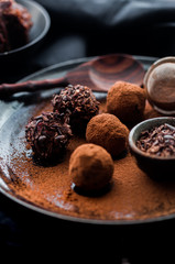Date energy ball with cocoa on a black dish and cocoa nibs