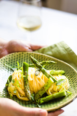 Pasta with asparagus and basil on a green ceramic and white surface
