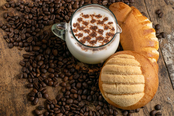copa de leche sobre mesa de madera rustica con granos de cafe cocoa y pan