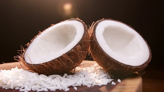 Coconut split in half with coconut shavings on top of a wooden board