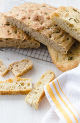 rosemary focaccia on a white surface and yellow kitchen towel