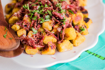 Banana gnocchi with jerk beef on a white ceramic