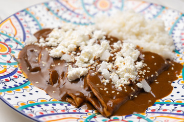 Mexican mole enchiladas with rice on white background