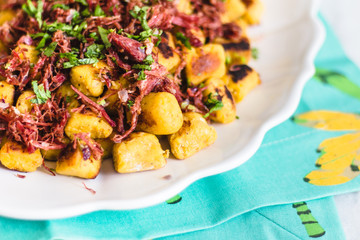 Banana gnocchi with jerk beef on a white ceramic