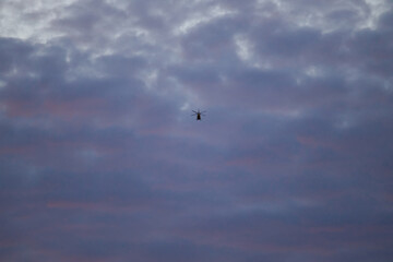 one helicopter fly in the pink clouds