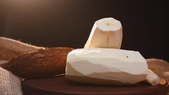 Peeled cassava and cassava in shell on a wooden plank