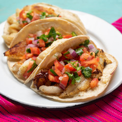 Mexican fish tacos also called Baja with fresh sauce on turquoise background