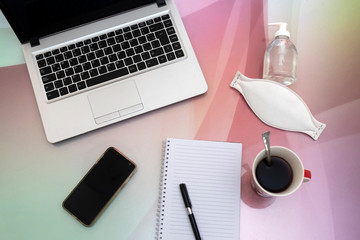 computadora sobre mesa con anotador lapicera una taza de cafe celular con barbijo y alcohol en gel para proteccion del covid-19 trabajo en casa 