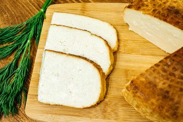 Sliced ​​cheese with herbs on a wooden board