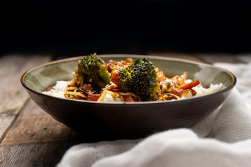 Thai style rice with fried vegetables and soy sauce on wooden background