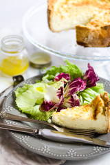 Quiche with colorful salad and dressing on a marble surface