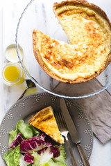 Quiche with colorful salad and dressing on a marble surface