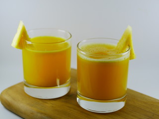 juice and slices of pineapple on wooden board