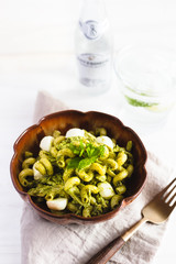 Homemade pasta salad with pesto and buffalo mozzarella on a white surface and rustic napkin