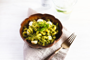 Homemade pasta salad with pesto and buffalo mozzarella on a white surface and rustic napkin