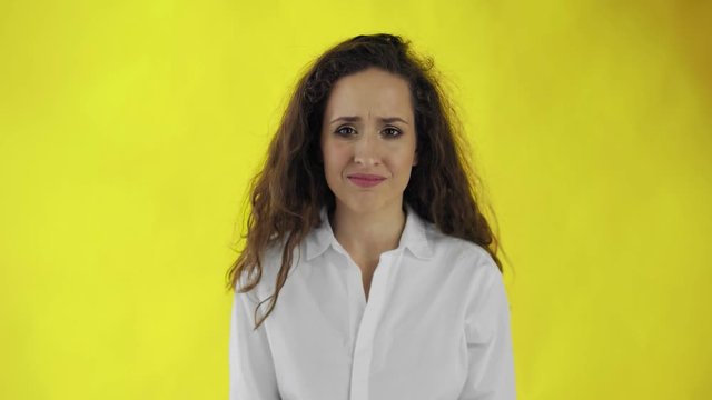 Portrait of a young woman feeling disgust on yellow background