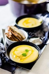 Creamy soup with toast on a white surface