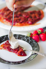 Strawberries tarte tatin with cream on a slice being served
