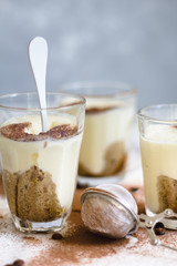 Tiramisu in a glass with cocoa powder on a marble and gray background
