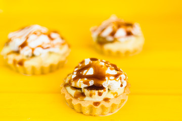 Banana pie with cream and caramel on a yellow background