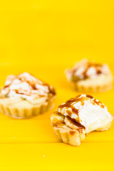 Banana pie with cream and caramel on a yellow background
