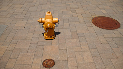 A yellow fire hydrant sits on an improved sidewalk