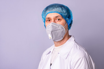 A doctor wearing medical respirator and uniform on blue background, isolated. COVID-19 protection.