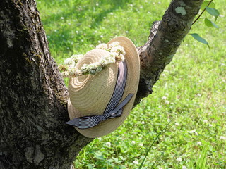 Women's straw hat and wreath on a tree branch