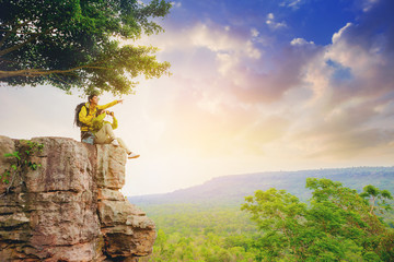 Couples hikers use binoculars to watching the view, sitting on top of the hill enjoy with nature