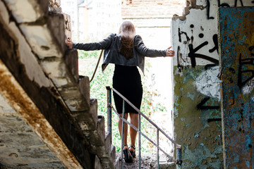 Elegant girl in a leather jacket in an abandoned building