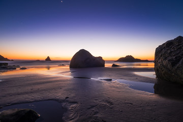 Fototapeta na wymiar Night beach of the sea or ocean at sunset. Rocks in the water. Night beautiful sky.