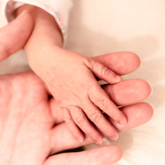 Mother's hand holding the hand of her newborn child