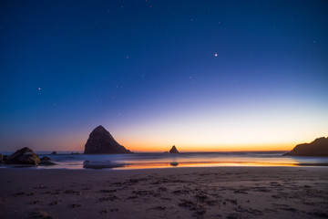 Naklejka na ściany i meble Night landscape on the pacific ocean, Cannon beach. Stars and cliffs, sunset time.