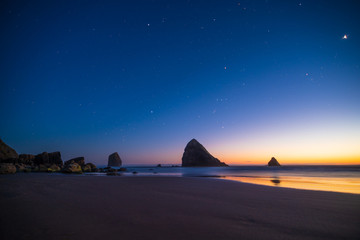 Fototapeta na wymiar Night landscape of pacific ocean beach in USA, cliffs, and night stars. Beautiful sunset