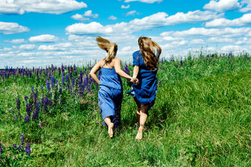 Fototapeta premium Two girls run in the summer field
